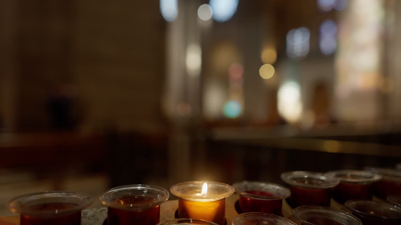Close up view of A candle flame flickers in The Basilica of the Sacred Heart of Paris.