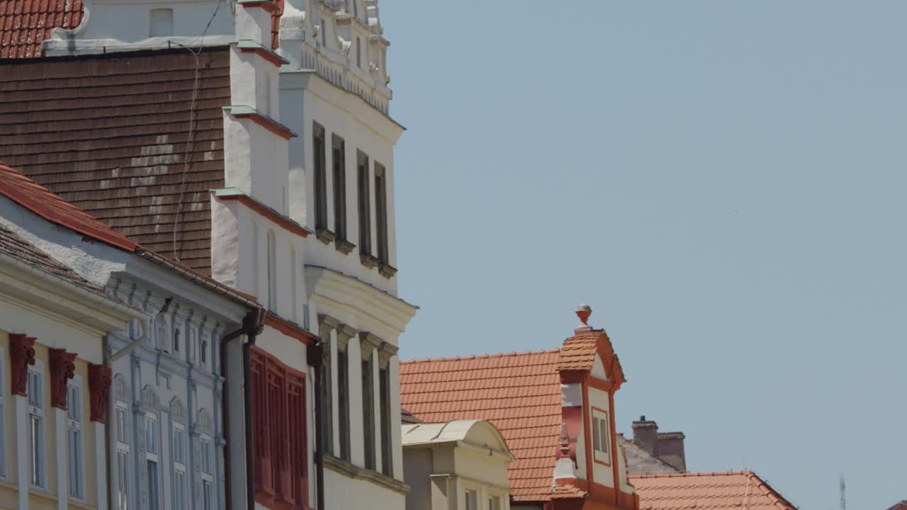 Camera slowly pans right, revealing ornate historic Prague rooftops under clear daylight sky