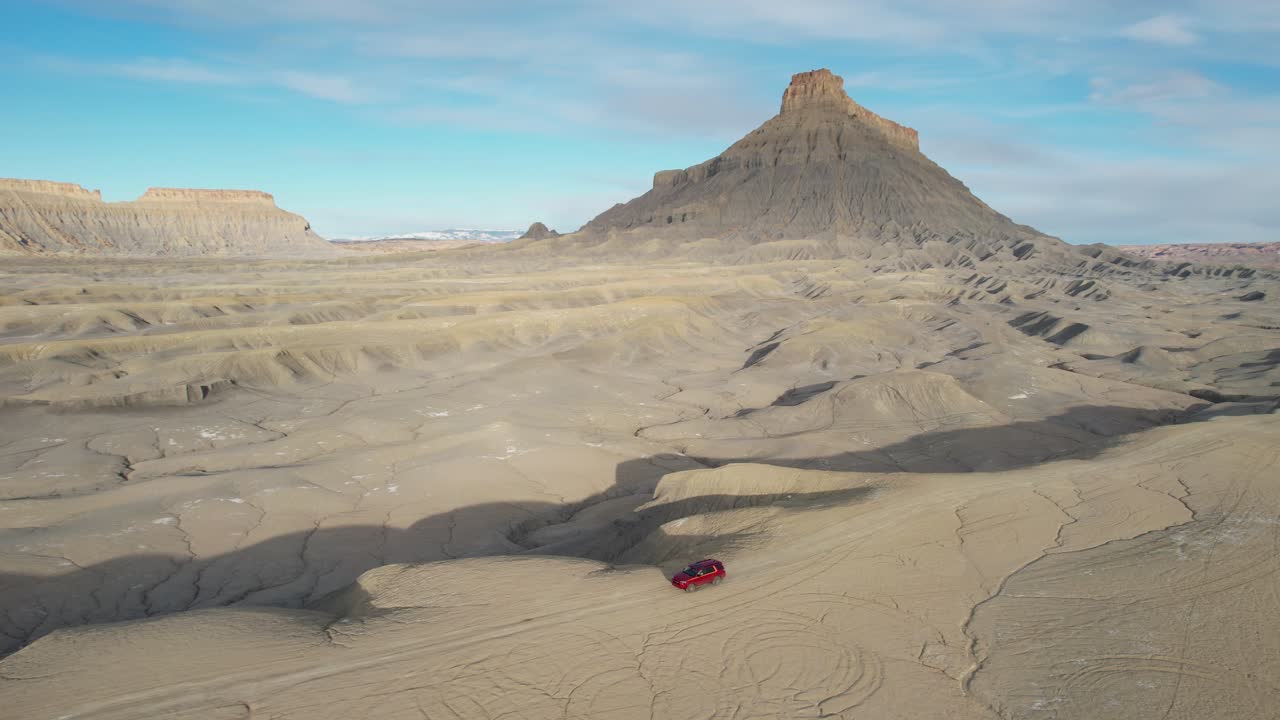공장 부트 근처의 유타의 사막 풍경에서 건조한 언덕에서 움직이는 빨간 suv 차량의 항공 사진, 드론  ⁇