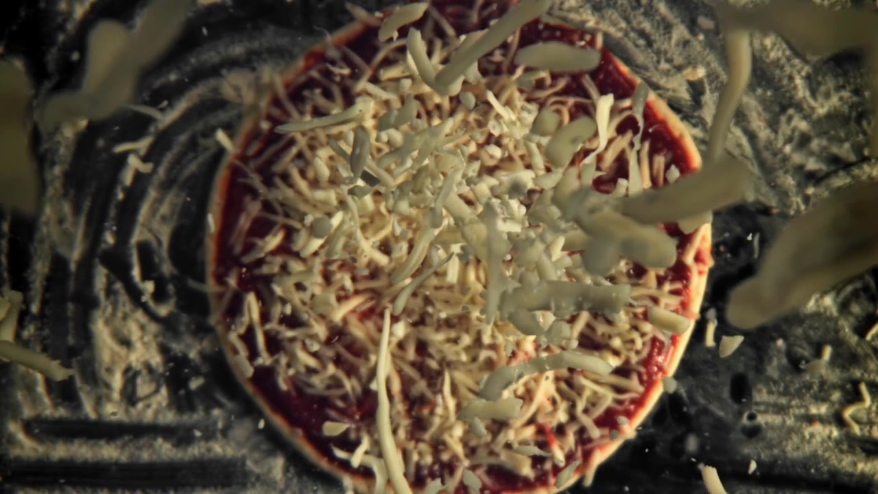 Formaggio grattugiato che cade su una pizza al rallentatore