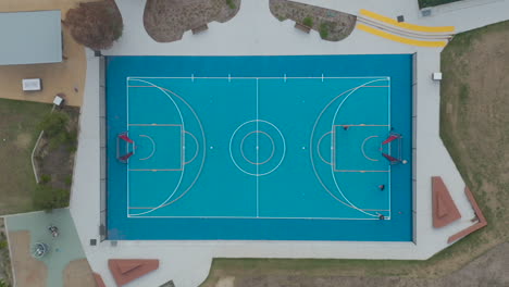 aerial static perspective of young people practicing basketball at a local community sports precinct