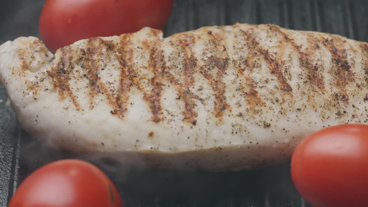 Close-Up of Cooking Chicken Breast with Whole Tomatoes on Grill