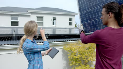 Pareja-Diversa-Ocupada-Usando-Tableta-Con-Espacio-Para-Copiar-Y-Llevando-Panel-Solar-En-El-Jardín,-Cámara-Lenta