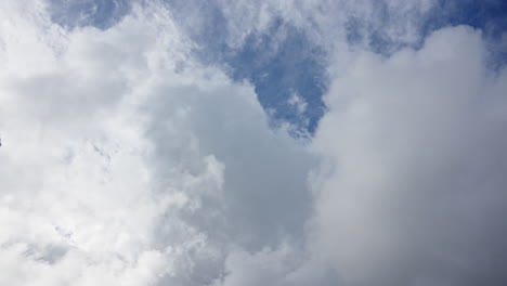 wide shot of a dynamic sky with drifting white clouds against a bright blue background, timelapse