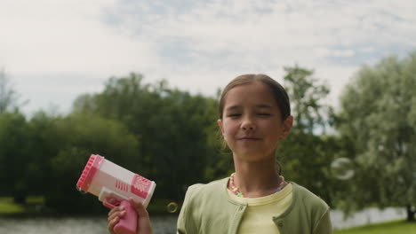 girl playing with bubble gun outdoors