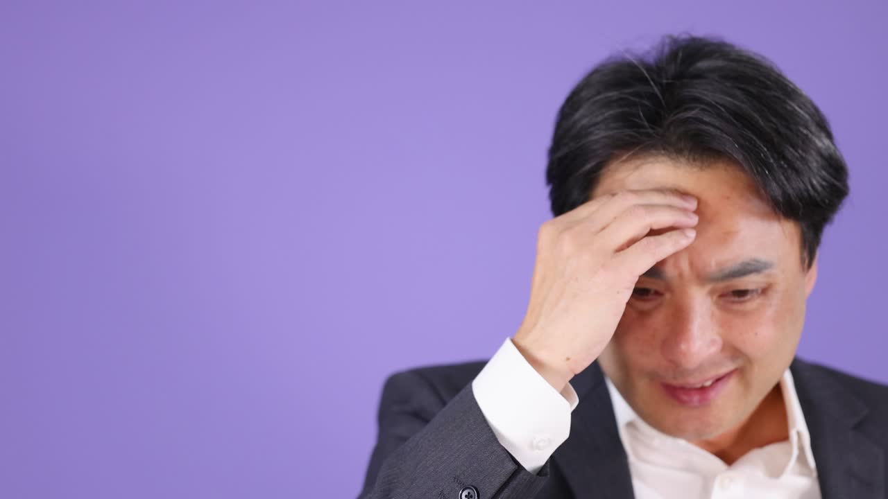 Businessman in office suit appears stressed, thinking deeply, under bright studio lighting, static camera