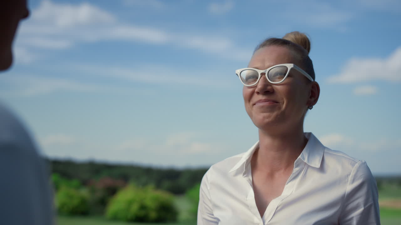 Krásná žena se usmívá venku na golfovém hřišti. Šťastná golfistka si užívá rozhovor.
