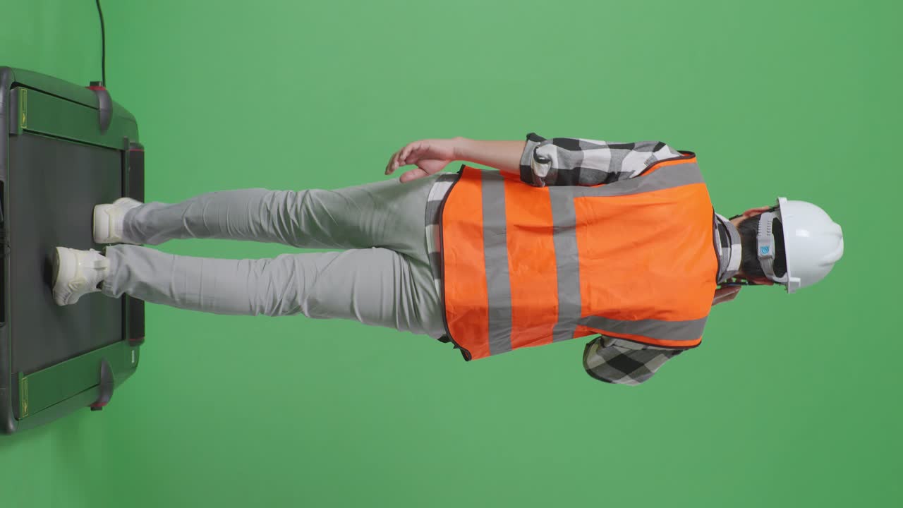 안전 헬을 착용한 아시아 남성 엔지니어가 녹색 스크린을 배경으로 는 동안 스마트폰으로 대화하는 모습