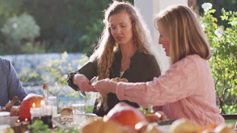 Video-Von-Glücklichen-Kaukasischen-Eltern-Und-Großeltern,-Die-Essen-Am-Tisch-Im-Freien-Servieren