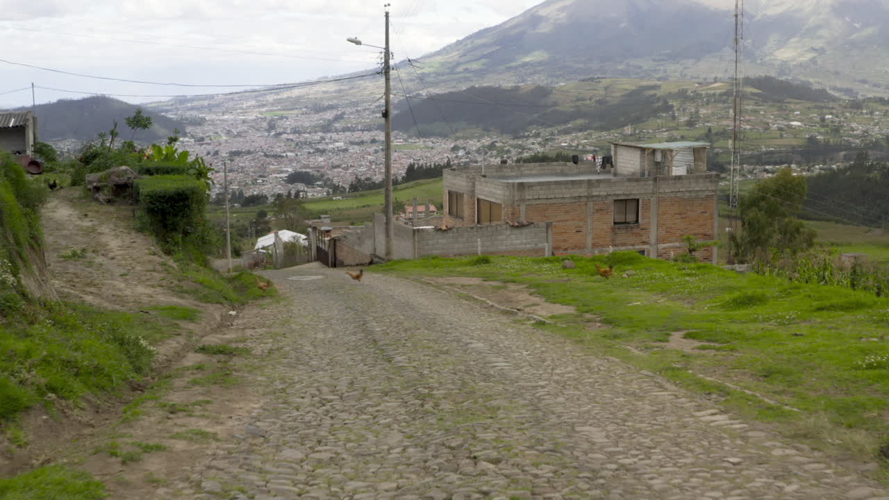 Cobblestone Road Leading Uphill Towards a Town in a Mountainous Landscape