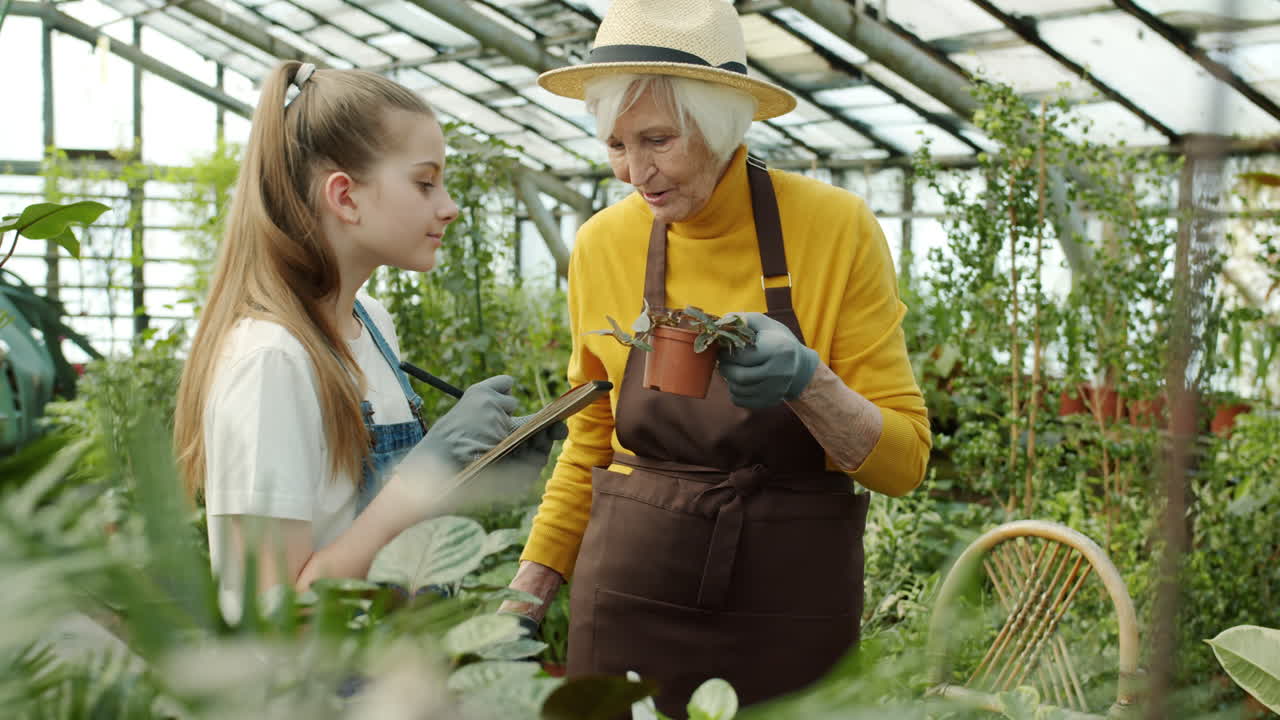 Grandmother and Granddaughter Inspecting Plants in a Greenhouse
