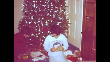 woman standing in front of christmas tree. circa usa - 1970s: a woman from a 1970s video archive in the usa stands in front of a festive christmas tree.