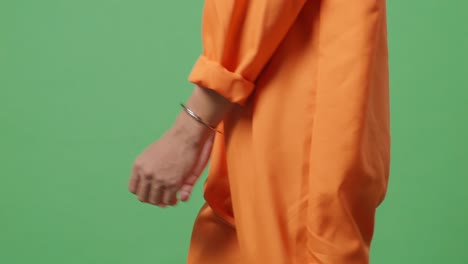 vista lateral de cerca de las manos del prisionero masculino en esposas mientras camina en el fondo de la pantalla verde