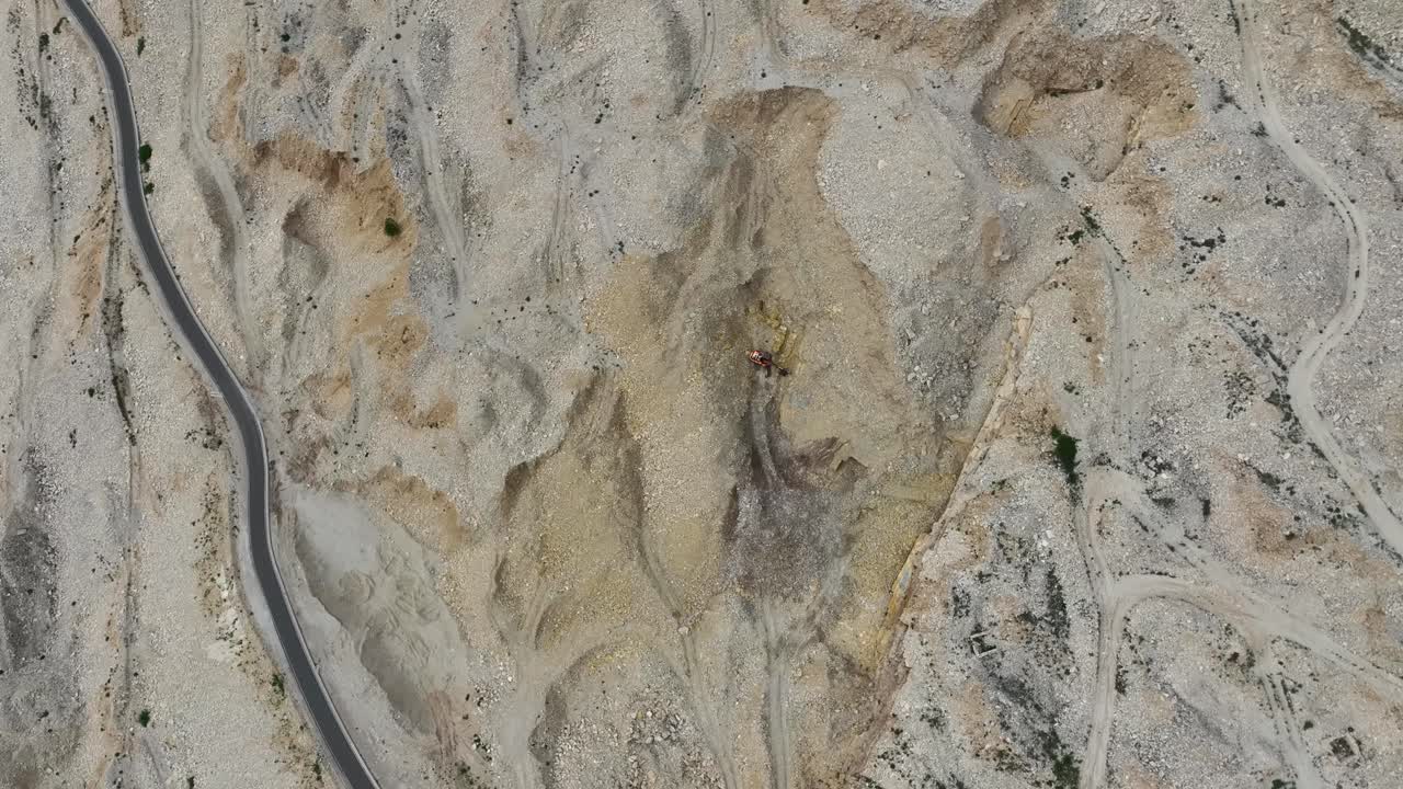 excavación en el lado de la montaña con una pequeña carretera ventosa cerca