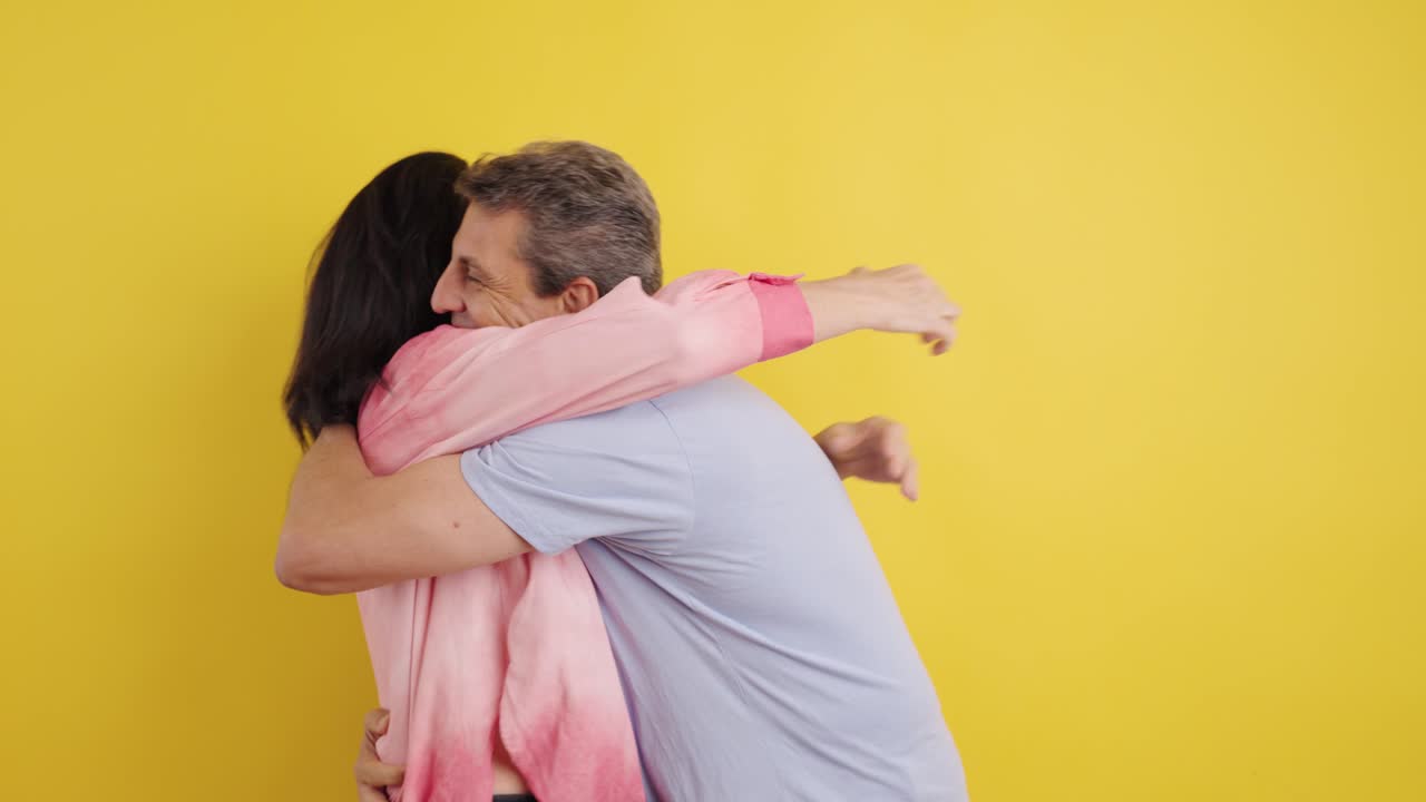 A couple celebrating good news against a yellow background