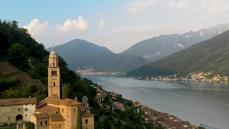 cinematic drone shot starting on lugano lake then revealing chiesa di santa maria del sasso in switzerland