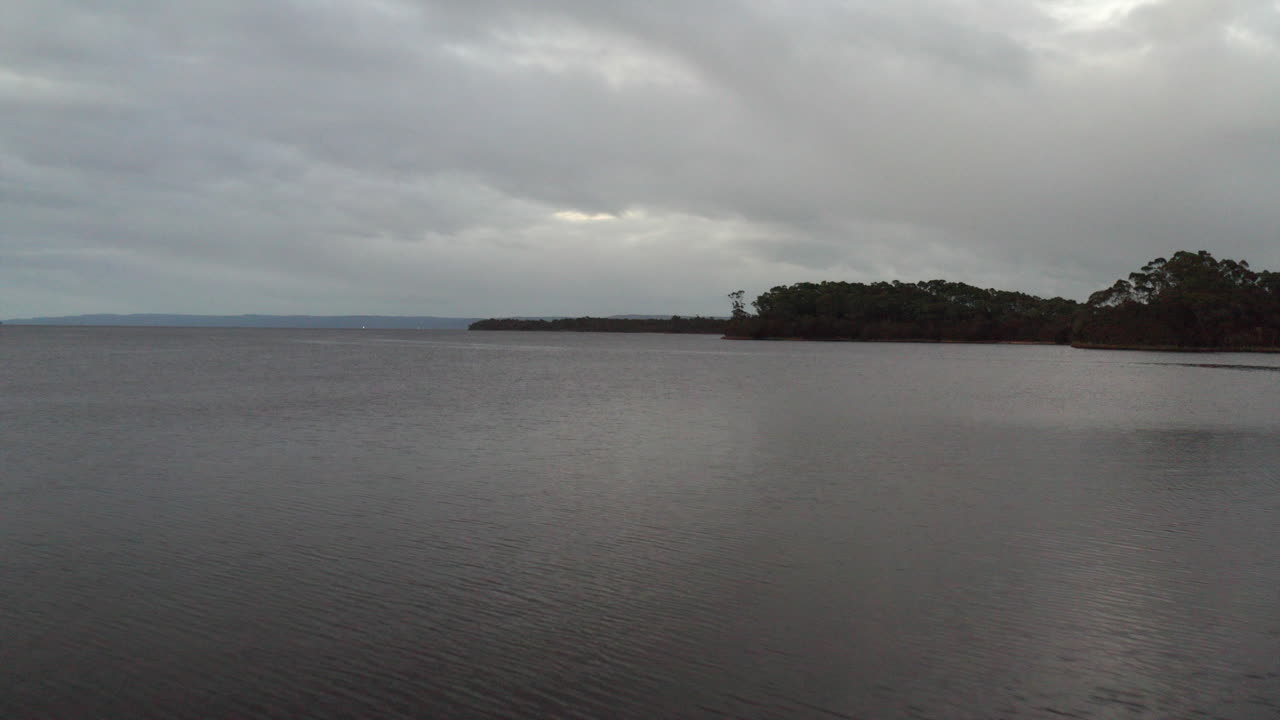antena: drone volando sobre un gran lago en un día nublado moody en la costa oeste de tasmania