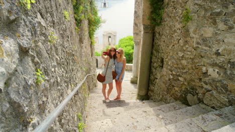 two women taking a selfie on a stone stairway in an old town