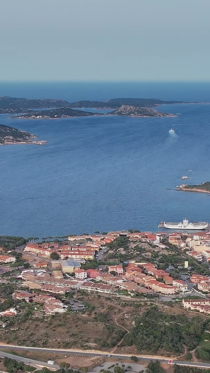 Vista della costa sarda con barche e acqua blu durante una giornata di sole