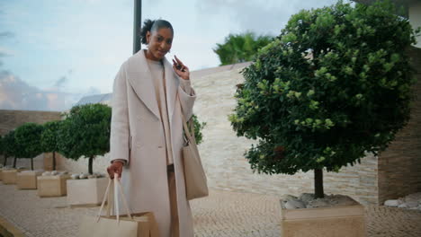 happy woman walking shopping bags on street. smiling african american enjoying