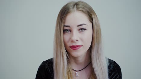 portrait of a beautiful girl with perfect make-up. blonde woman with long hair looking on camera and smiling on grey studio background.