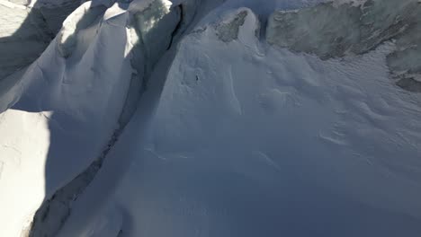 aéreo, inclinado hacia arriba: grietas cubiertas de nieve, montañas de los alpes suizos