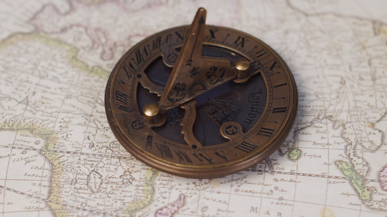 An atique brass sundial navigational instrument on a vintage world map