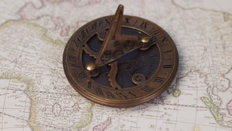 un antiguo instrumento de navegación de reloj de sol de latón en un mapa del mundo antiguo