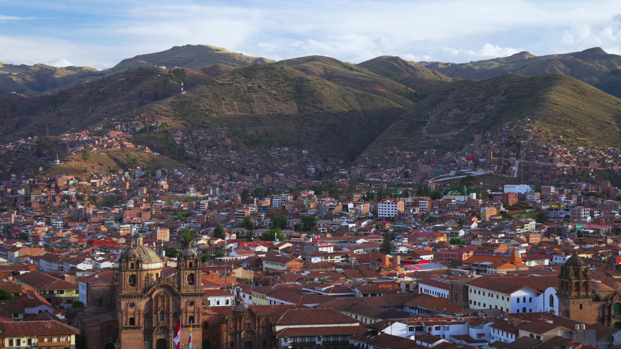 Cusco Cathedral Plaza de Armas main square city of Cuzco Peru cityscape landscape rainy season sunset golden hour clouds Peruvian neighborhood buildings on mountainside Anta Province Andes static shot