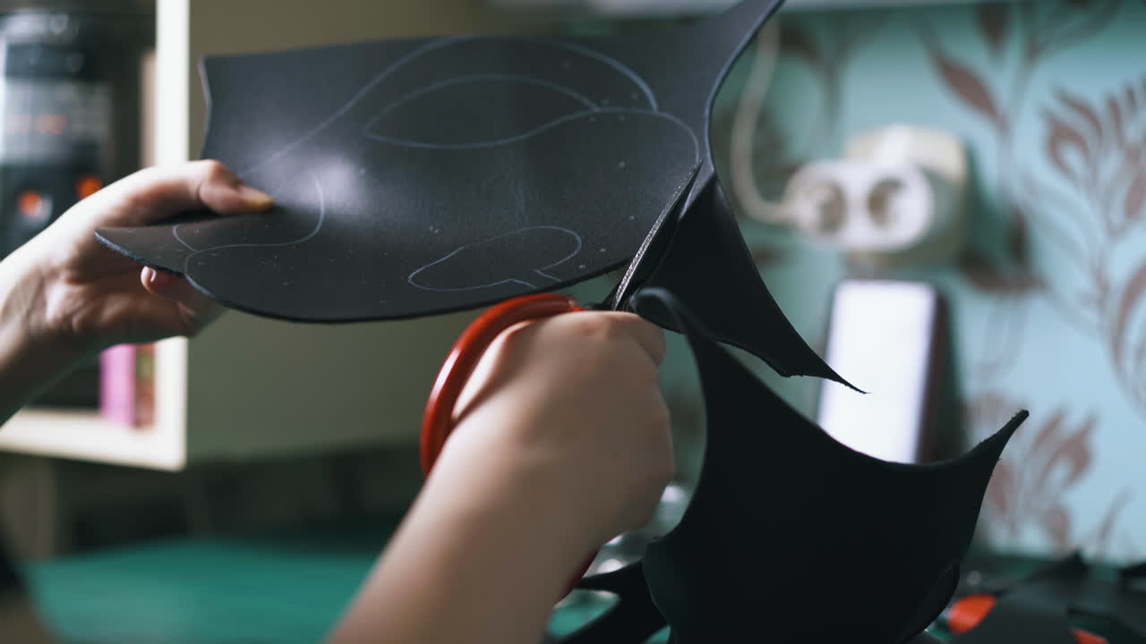 el sastre hábil corta tela de cuero negro contra el multicooker