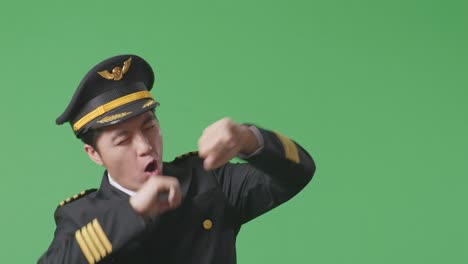 close up of asian man pilot dancing and celebrating while standing in the green screen background studio