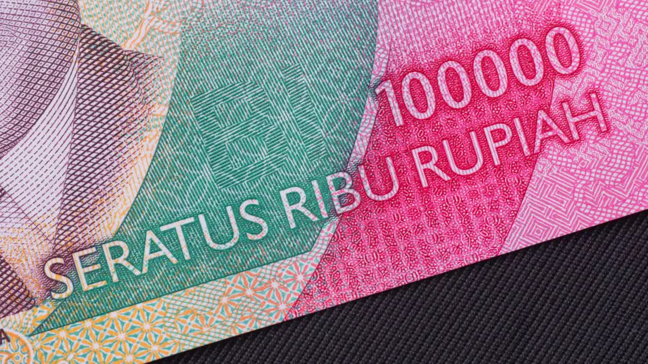 Memperlihatkan uang kertas seratus ribu rupiah, mata uang Indonesia, pengambilan gambar close-up makro yang detail.