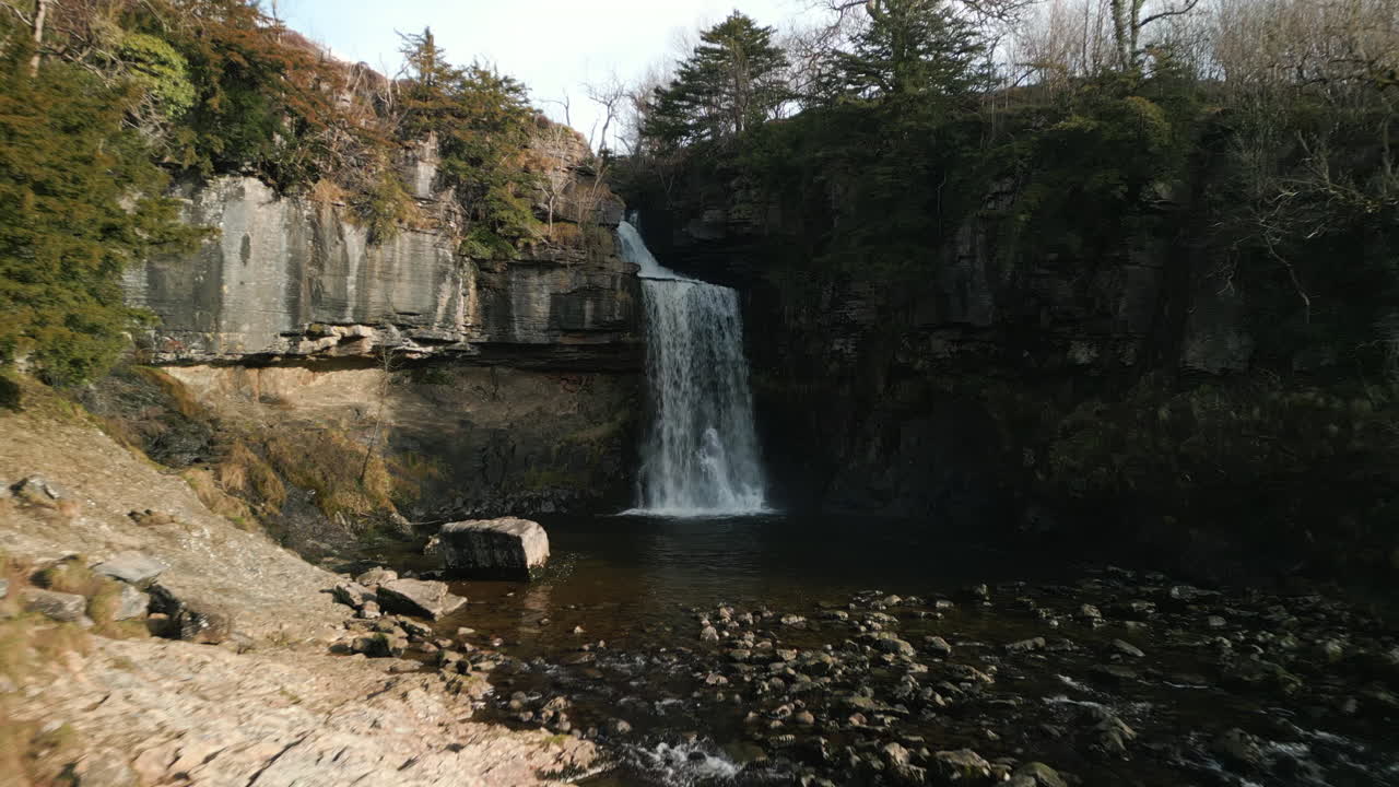 Cascata che si rivela con una ripresa in allontanamento nella campagna inglese, Ingleton Waterfalls Trail, Yorkshire, Regno Unito.