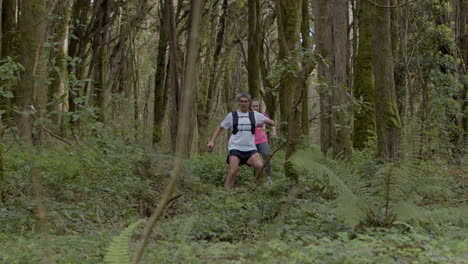 fit man and woman running on forest trail