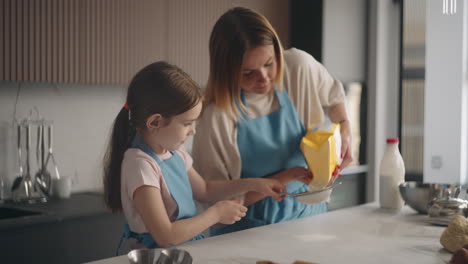 Mutter-Bringt-Ihrem-Kleinen-Mädchen-Bei,-Teig-Zu-Machen-Und-Brot-Zu-Backen,-Zu-Hause-Gießt-Frau-Mehl-In-Ein-Sieb