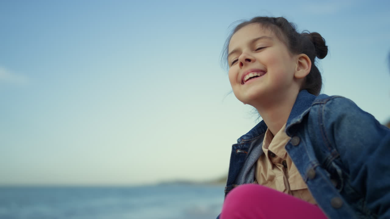 Smiling girl enjoy sea beach on summer holiday. Happy kid looking ocean nature.