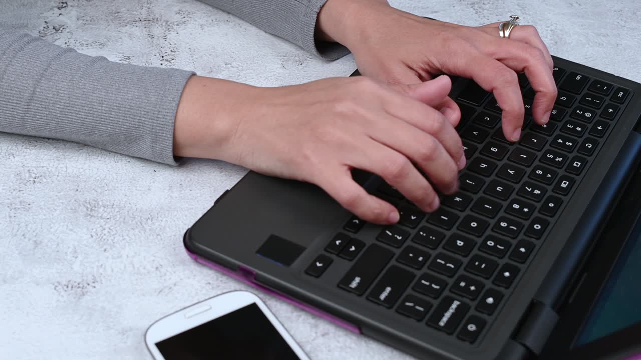 cerca de las manos de la mujer trabajando y escribiendo en el teclado de la computadora portátil.