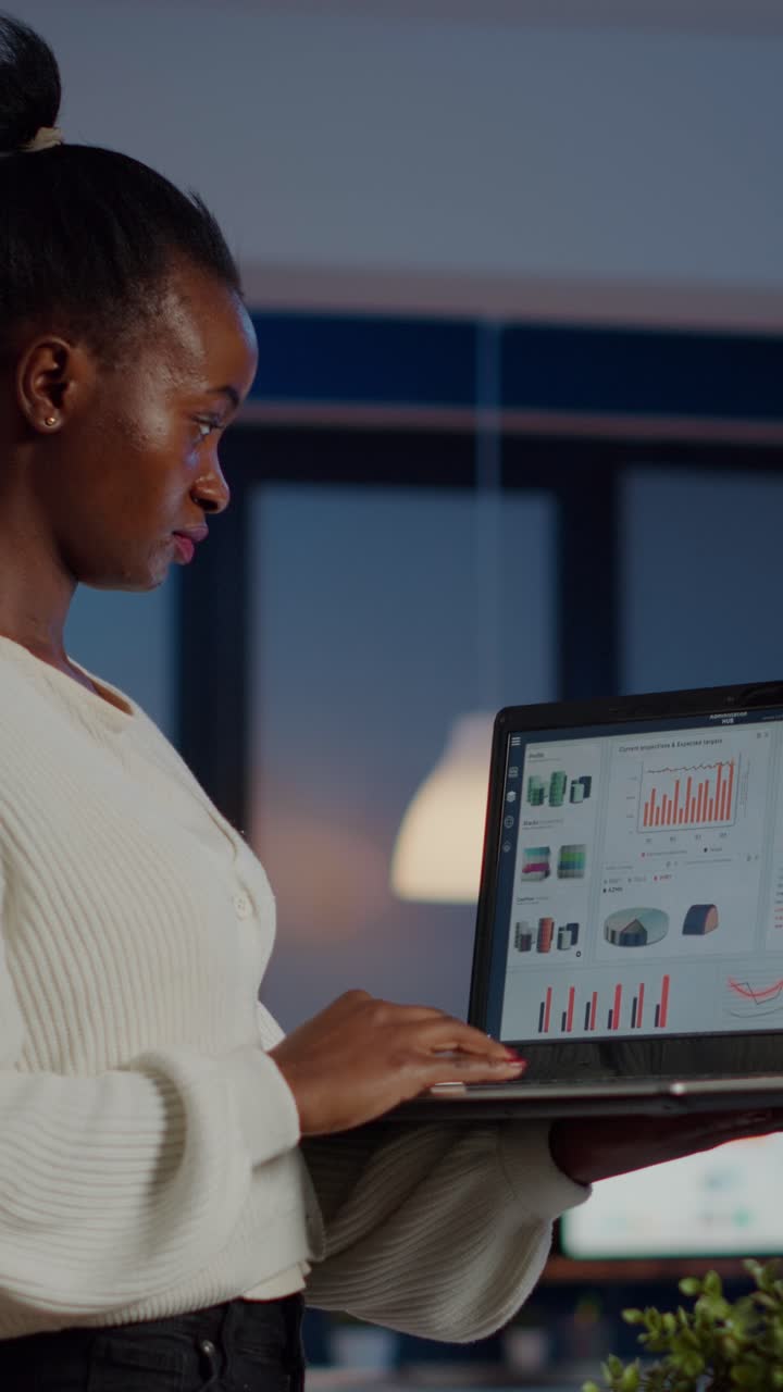 Vertical video Focused black manager woman checking business report holding laptop