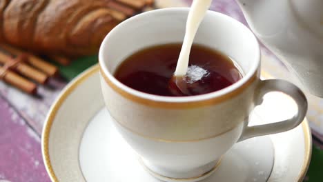 pouring milk into cup with tea