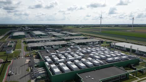 aerial footage showing a sustainable data center in eemshaven surrounded by dutch countryside and wind turbines. technology and renewable energy in harmony