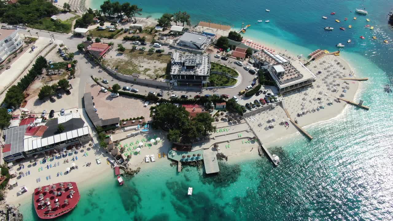 알바니아에서 드론이 하 모래 해변, 푸른 크리스탈 은 물, 자루, 보트 및 호텔을 날아다니는 풍경.