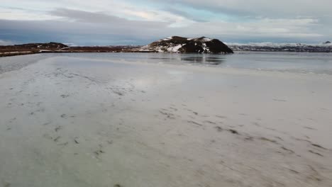 low aerial flight drone over frozen lake to volcano in iceland