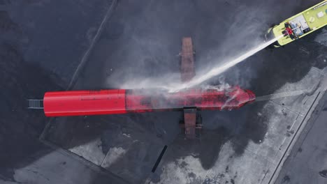 camión de bomberos scania extinguiendo el incendio de un avión réplica durante el entrenamiento