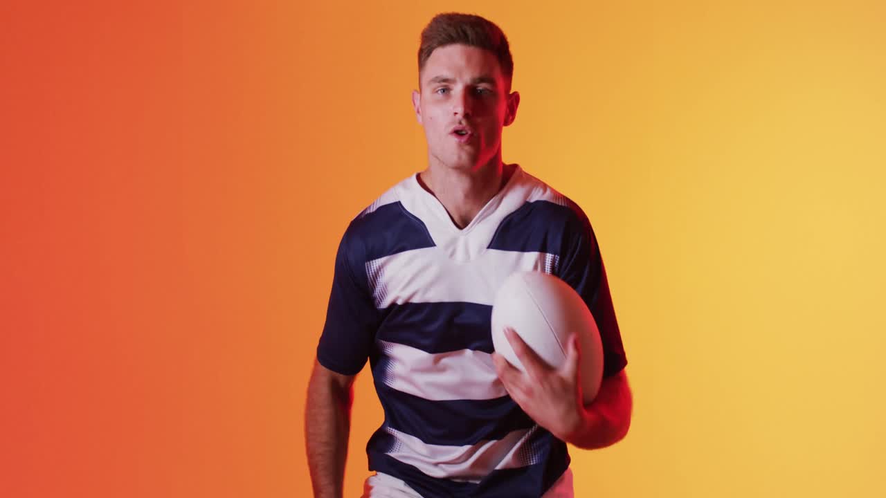 retrato de un jugador de rugby caucásico corriendo con una pelota de rugby sobre una iluminación naranja
