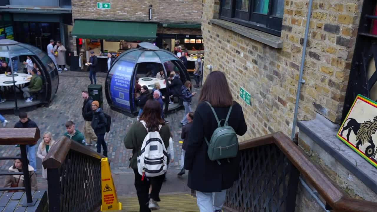 Tourists descend stairs toward outdoor dining bubbles in Camden Town's bustling food market