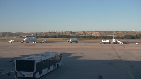closer shot of aircrafts boarding and loading luggage with an airplane is landing in the back
