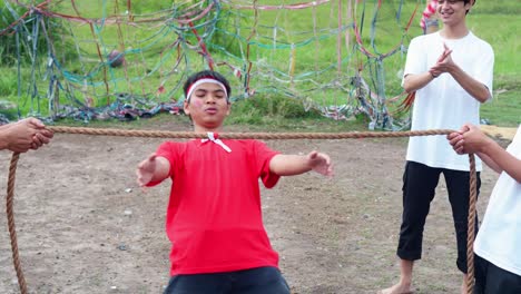 funny young asian man engaging traditional game during indonesian independence day with friends
