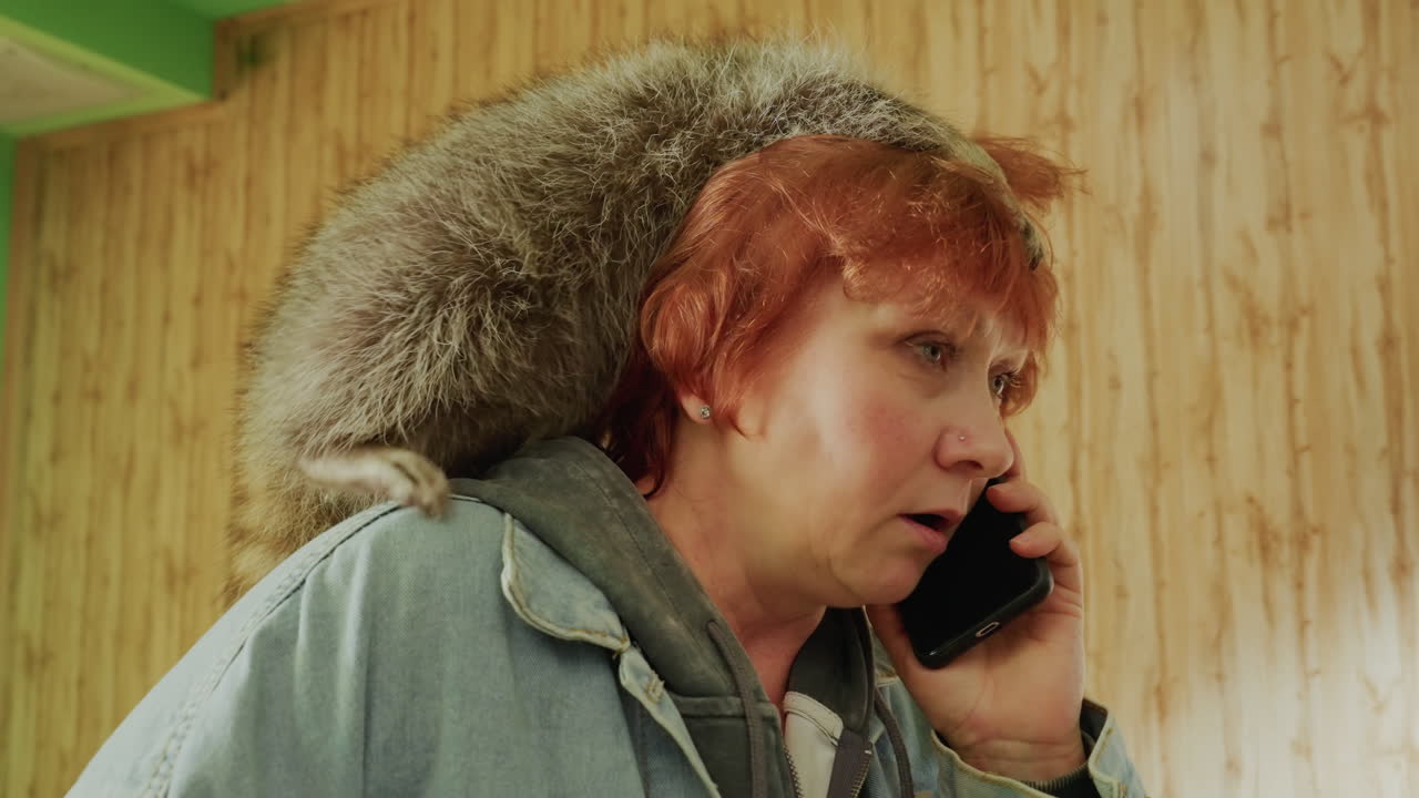 Kafasında rakun tünemiş, retro bir odanın içinde telefonla konuşan beyaz tenli kadın, kot ceketli ve kızıl saçlı, animasyonlu endişeli ifadeler, acil bir vahşi yaşam sorununu yanıtlarken küçük bir kurtarma hayvanıyla ilgileniyor