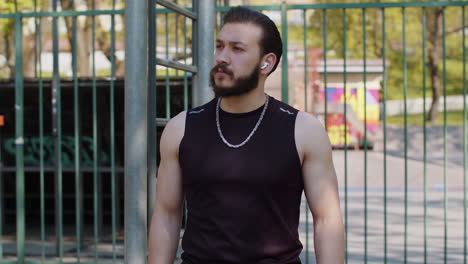 athletic lebanese man in sportswear enjoying listening to music in earphones from smartphone app