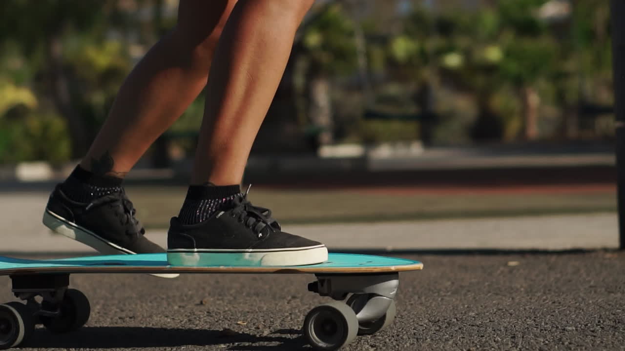 Amidst palm trees, slow motion showcases a young woman enjoying a longboard ride in the summer, dressed in shorts and sneakers